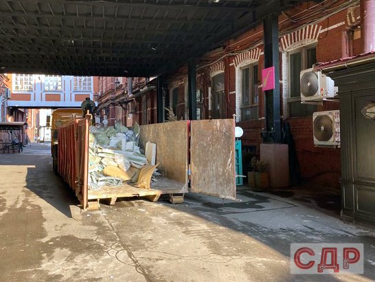 Вывоз мусора в большом строительном контейнере.